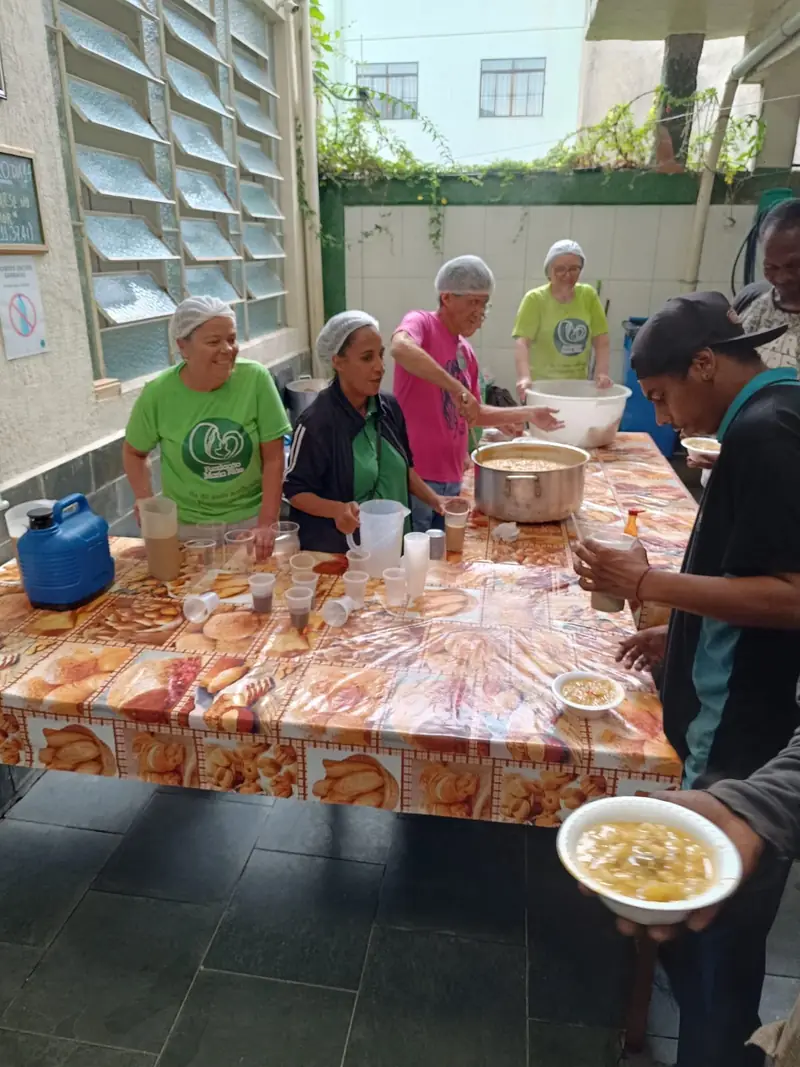 Mesa com pães embalados e café servido no salão da Obra